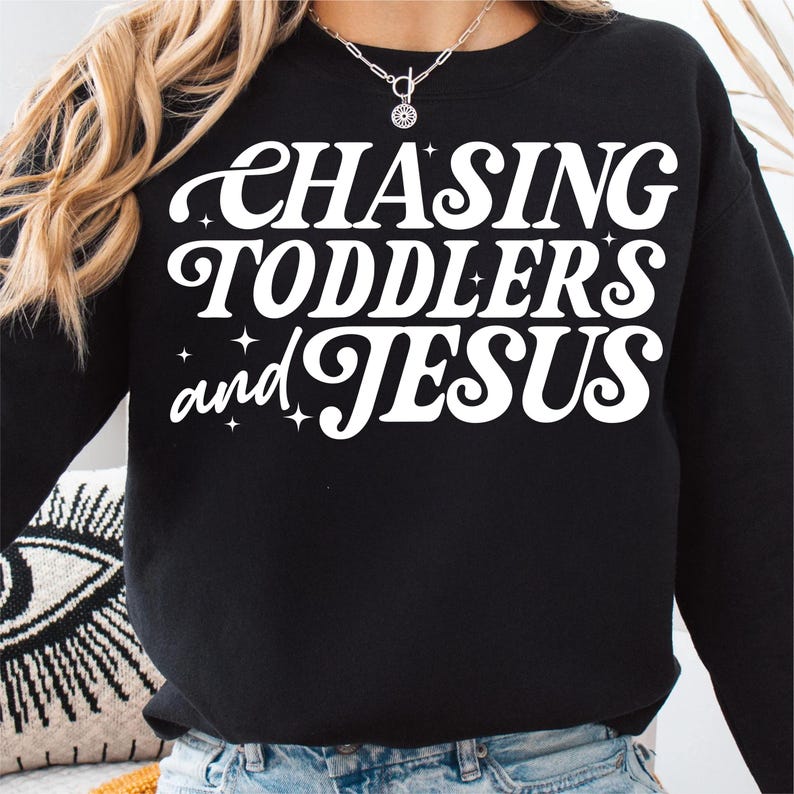 May include: Black sweatshirt with white text that reads "Chasing Toddlers and Jesus" in a retro font.