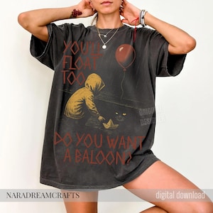 May include: Dark gray t-shirt with a distressed graphic featuring a hooded figure, a paper boat, and a red balloon. Text reads "YOU'LL FLOAT TOO" and "DO YOU WANT A BALLOON?" The shirt has a vintage look.
