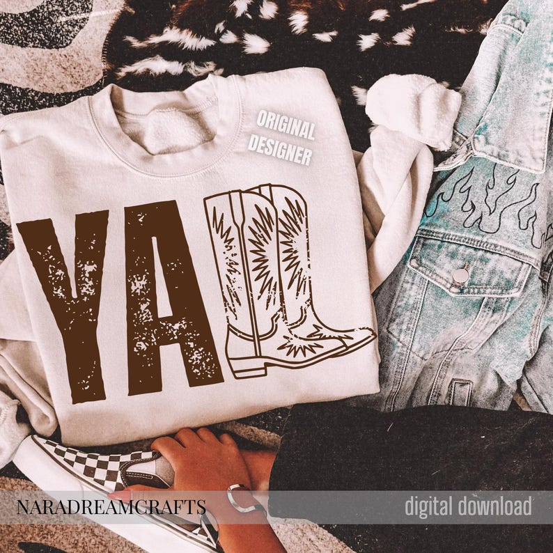 May include: A cream-colored sweatshirt with the word "YA" in distressed brown letters and a brown cowboy boot graphic. The words "ORIGINAL DESIGNER" are printed on the top right. A denim jacket and checkered shoes are also visible.