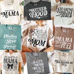 Può includere: Un collage di dieci diversi design di magliette con slogan sul tema della maternità. Gli slogan includono "One Loved Mama", "Motherhood", "Chasing Toddlers and Jesus", "Mothers Plant Seeds of Love That Bloom Forever", "She is Strong, Brave, Fearless, Loving, Kind, Beautiful Mom", "Mama Hands and Heart Full", "Mama", "Salty Moms Beach Club", e "Everything I Am You Helped Me To Be".