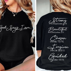 Może przedstawiać: Czarny sweter z białym napisem "God Says I am..." z przodu i "Strong Philippians 4:13, Beautiful Ecclesiastes 3:11, Chosen John 15:16, Forgiven Psalm 103:12, Guided Psalms 48:14" z tyłu.