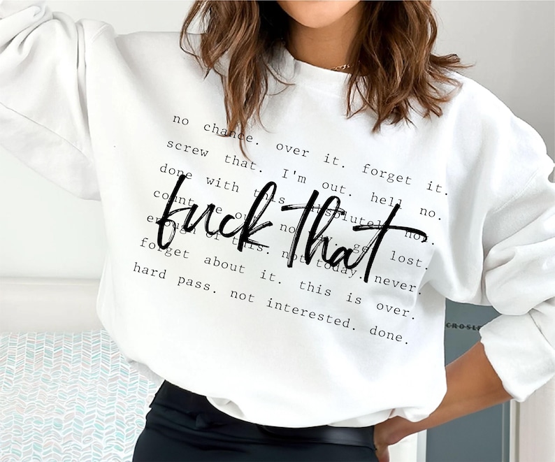 May include: White sweatshirt with the phrase "fuck that" in a bold, black script. Surrounding the phrase are smaller black text phrases like "no chance," "forget it," and "hard pass." The sweatshirt is a casual, comfortable style.