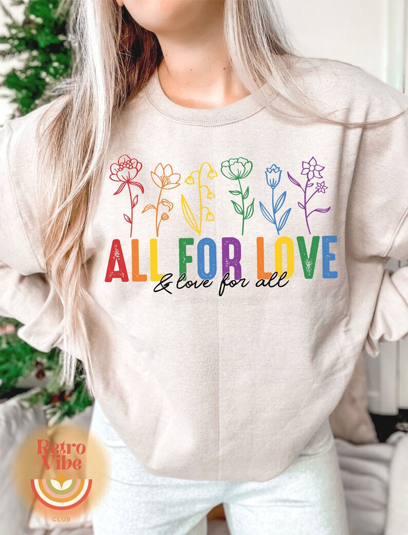 Puede incluir: Una sudadera beige con un dise&ntilde;o de arco&iacute;ris de flores y el texto "All for Love & love for all".