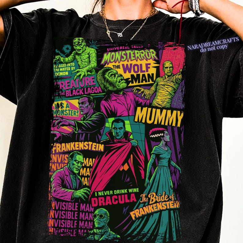 May include: Black t-shirt featuring a colorful graphic of classic Universal Monsters. The design includes images of the Wolfman, Mummy, Dracula, Frankenstein, and the Creature from the Black Lagoon, with text that reads "Monsteror".