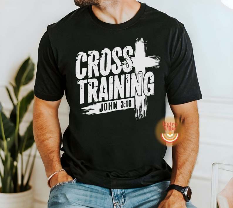 May include: Black t-shirt with the white text "CROSS TRAINING" and "JOHN 3:16" in a distressed font. A white cross graphic is behind the text. The shirt is a crew neck style.