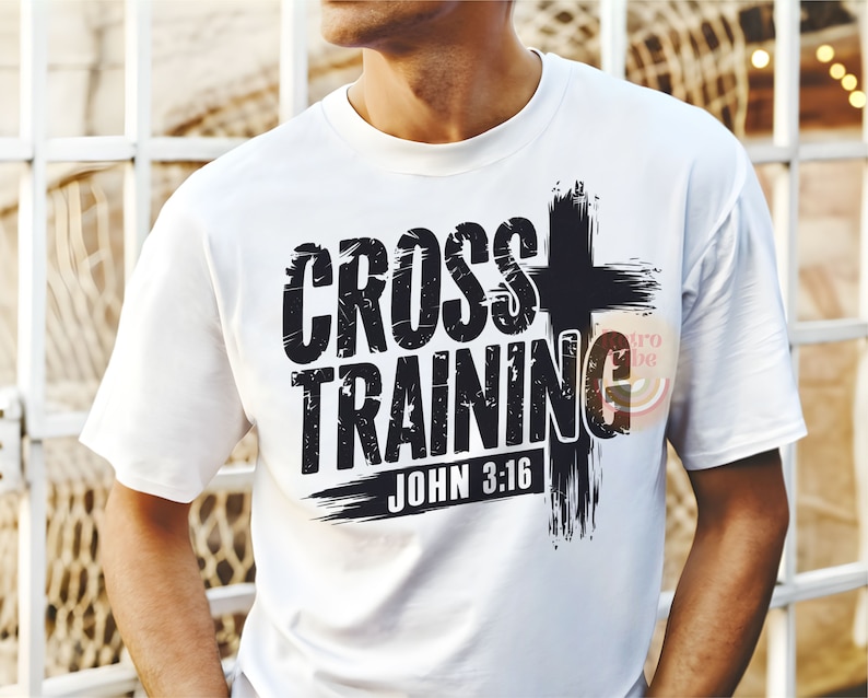 May include: White t-shirt with the words "CROSS TRAINING" in a distressed black font, accompanied by a black cross graphic. The text "JOHN 3:16" is below the main text. The shirt is a casual wear item.