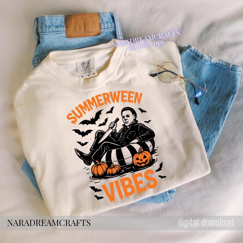 Op de afbeelding: Cr&egrave;mekleurige sweatshirt met de woorden "SUMMERWEEN VIBES" in oranje, met een afbeelding van een personage met een mes, pompoenen en vleermuizen. Het shirt ligt op een blauwe jeans.
