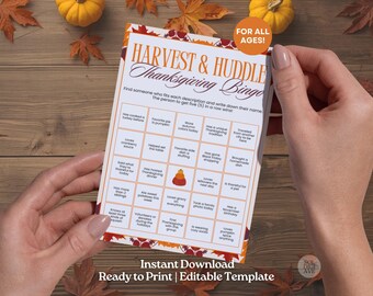 以下が含まれることがあります： 「Harvest & Huddle Thanksgiving Bingo」と「For All Ages!」というオレンジと茶色の文字が入った、感謝祭のビンゴカード。カードは人の手で持たれており、秋の葉とカボチャに囲まれています。