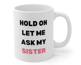 May include: White ceramic mug with the text "HOLD ON LET ME ASK MY SISTER" in black and pink lettering. The mug has a curved handle and a glossy finish.