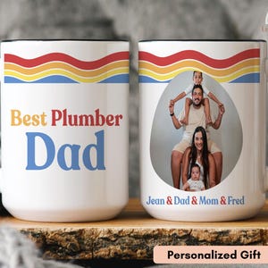 May include: White ceramic mug with a black handle and rim, displaying the text "Best Plumber Dad" in red and blue. The mug also has a family photo and the text "Jean & Dad & Mom & Fred". A personalized gift.