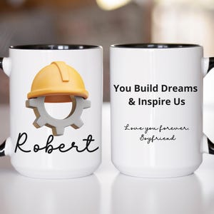 Puede incluir: Taza de cerámica blanca con asa y borde negros. Presenta un casco de construcción amarillo y un engranaje, el nombre "Robert" y el texto "You Build Dreams & Inspire Us. Love you forever, Boyfriend."
