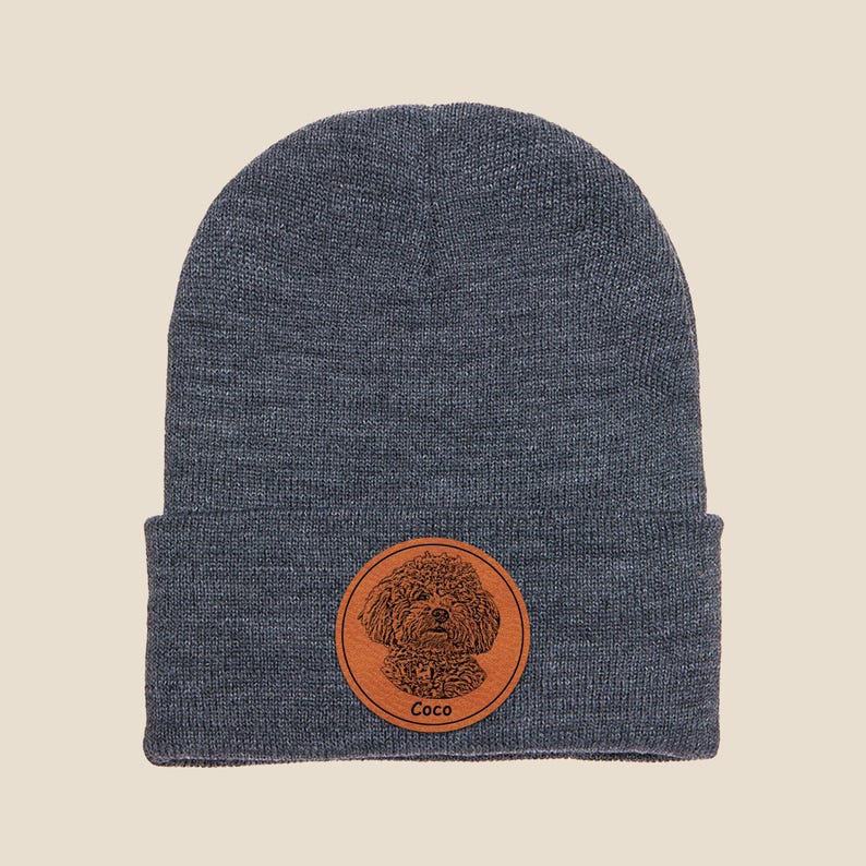 May include: A dark gray beanie with a brown leather patch featuring a dog's portrait and the name "Coco".