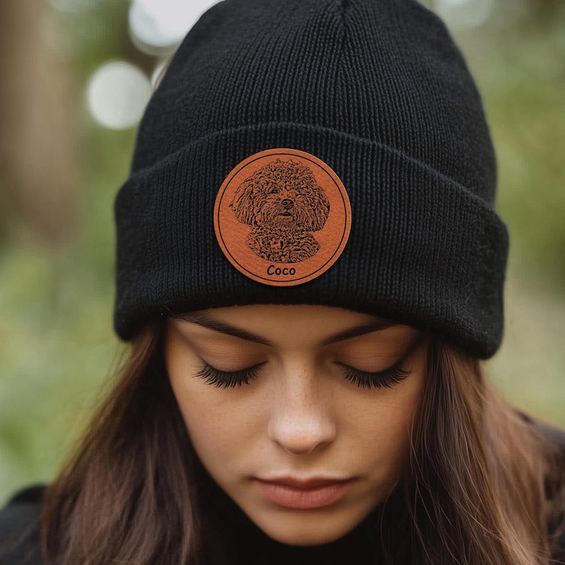 May include: Black beanie with a brown leather patch featuring a dog's face and the name "Coco" in white text.