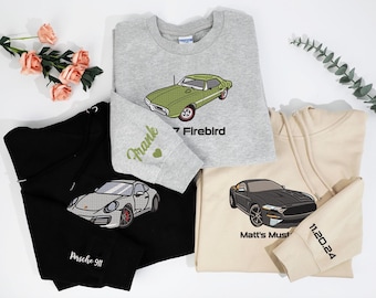 May include: Three sweatshirts with embroidered car designs. A gray sweatshirt with a green car and the text "Frank '7 Firebird". A black sweatshirt with a gray car and the text "Porsche 911". A beige sweatshirt with a black car and the text "Matt's Mustang 11.20.24".