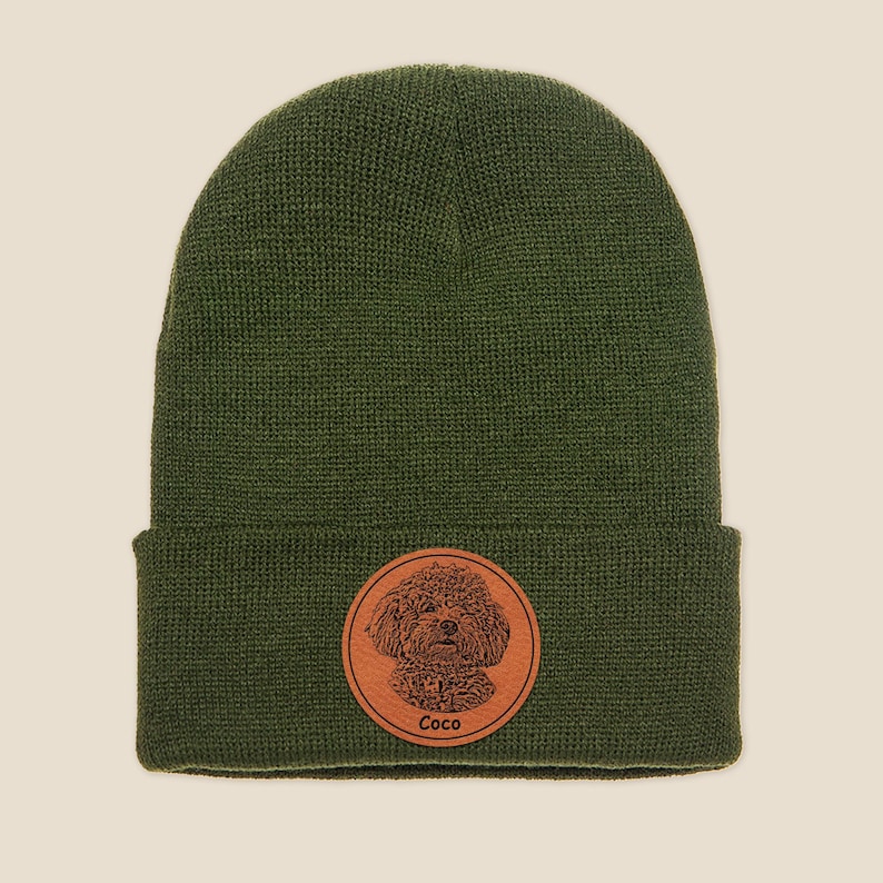 May include: A green knitted beanie with a brown leather patch featuring a dog's face and the name "Coco".