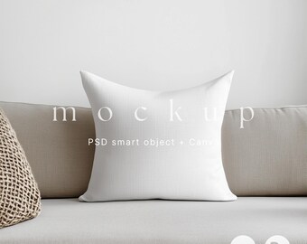 May include: A white square pillow with the word "mockup" printed on it, resting on a light gray sofa. The text "PSD smart object + Canva" is below the word "mockup". The pillow is a neutral home decor item.