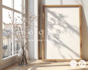 May include: A wooden frame with a white background sits on a wooden surface. A vase with white flowers sits on a windowsill in the background. The text "Mockup PSD smart object (5x7") Canva" is visible in the image.
