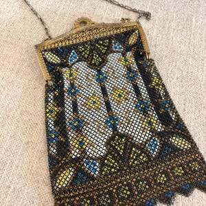 May include: An antique beaded handbag with a gold-tone frame and chain handle. The bag features a geometric pattern in black, white, yellow, and blue beads. The frame has an ornate design.