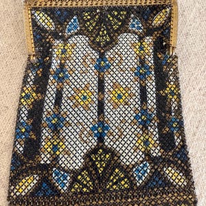 May include: An antique beaded handbag with a gold-toned frame and chain. The bag features a geometric pattern in black, white, yellow, and blue beads. The frame has an ornate design.