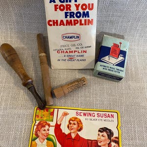 May include: A collection of vintage sewing tools and accessories. Includes a booklet from Champlin Oil, a needle threader, a card of Sewing Susan needles, and several wooden-handled tools.