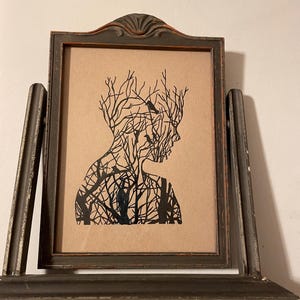 May include: A framed black and white silhouette print of a person with a tree growing out of their head. The tree has branches and birds perched on them.