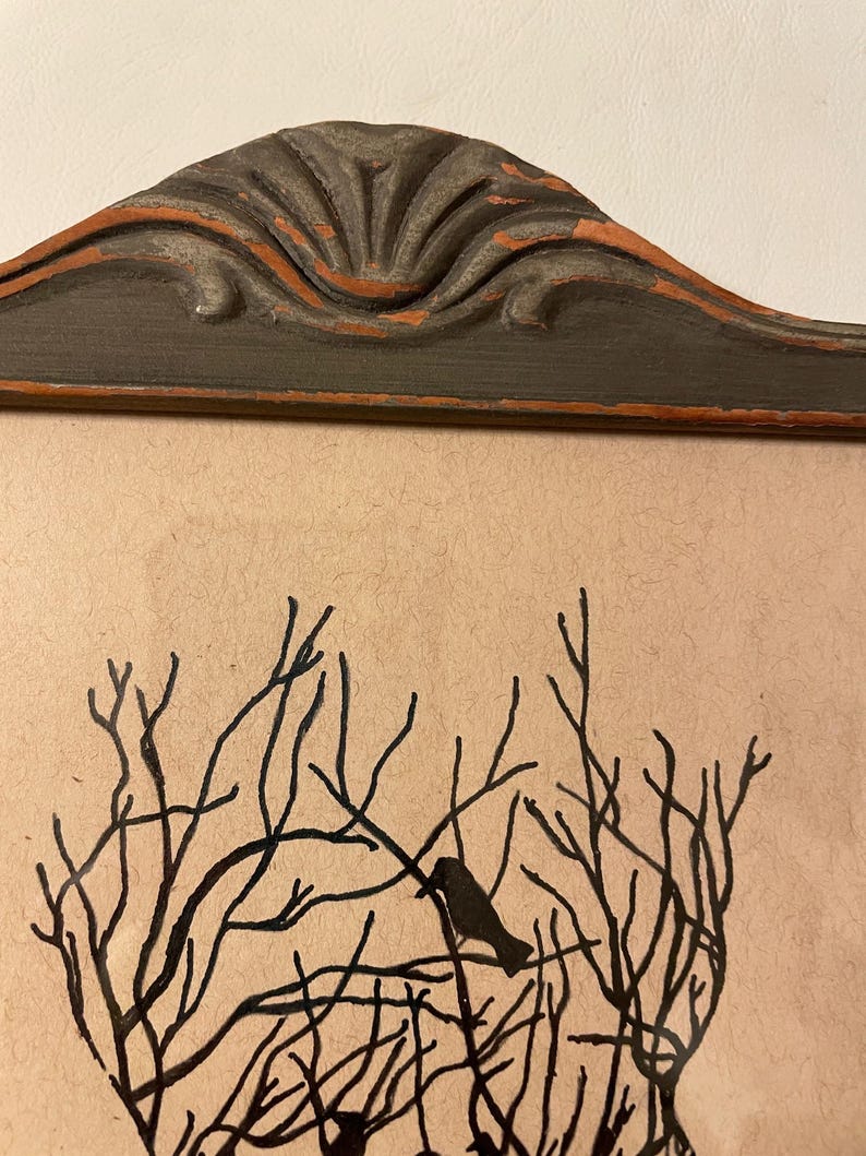 May include: A black and white illustration of a tree with birds perched on the branches. The illustration is framed in a dark gray frame with a decorative top.