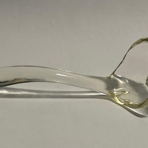 May include: A clear glass ladle with a long handle. The ladle is designed for serving liquids.