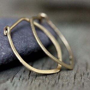 Op de afbeelding: Een paar gouden oorringen met een licht ovale vorm. De oorringen zijn gemaakt van dik, getextureerd draad.