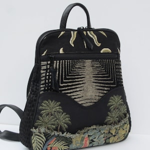 May include: Black backpack with a geometric pattern and embroidered palm trees. The backpack has a zip closure and a top handle.