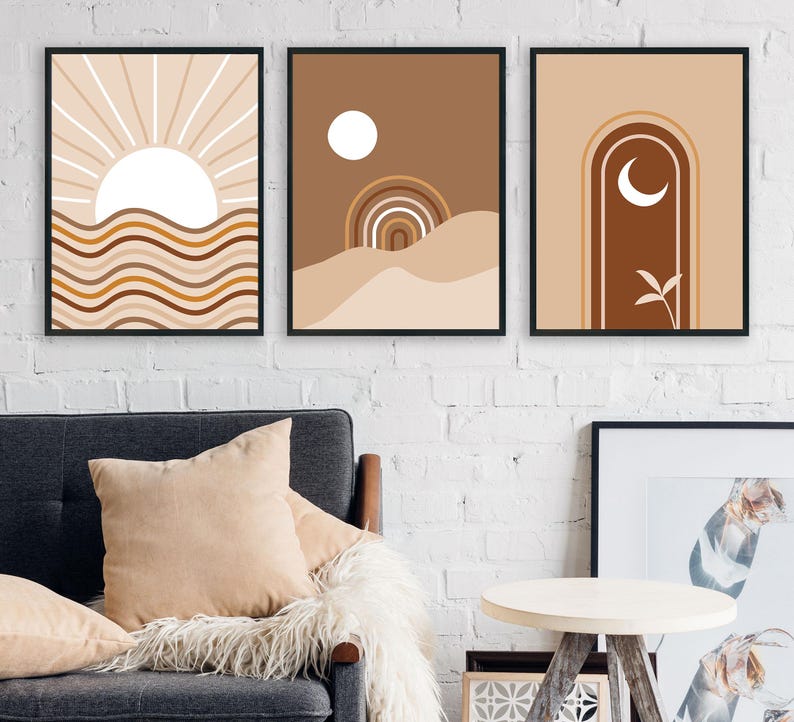 Op de afbeelding: Drie abstracte kunstprints met een minimalistisch ontwerp. De prints tonen een zon, een halve maan en een geometrische boog. De prints zijn in tinten bruin, beige en wit.