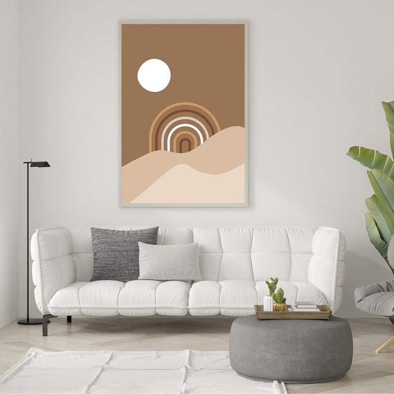 Op de afbeelding: Een digitale kunstprint met een minimalistisch abstract ontwerp met een witte cirkel, een regenboogvormige boog en bruine en beige golvende lijnen. De print is ingelijst en hangt aan een witte muur.