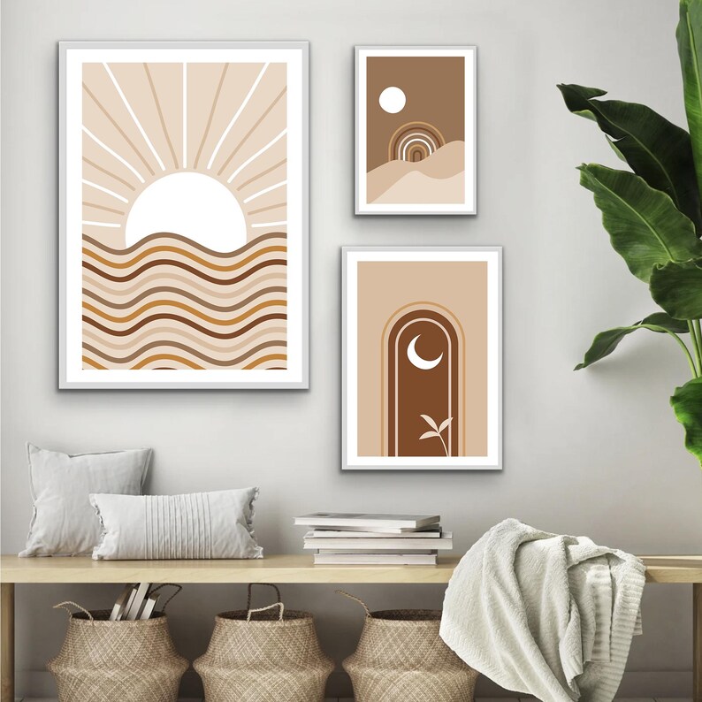 Op de afbeelding: Drie abstracte kunstprints met een minimalistisch ontwerp met een zon, maan en boog in tinten bruin, beige en wit.