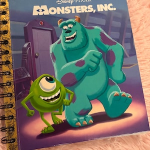 May include: A spiral-bound notebook featuring the cover of a Disney Pixar Monsters, Inc. Little Golden Book. The cover displays the characters Sulley and Mike Wazowski in front of a door. The spine is yellow with black line art illustrations.