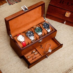 May include: A wooden watch box with a drawer. The box has a brown finish and is lined with a brown velvet-like material. The box has five slots for watches and a drawer for storing jewelry. The drawer has a small lock and key.