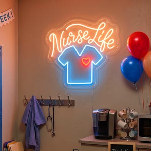 May include: A neon sign displaying the text Nurse Life in orange script above a blue outline of a scrub top with a small orange heart. The sign is mounted on a wall next to a red, a blue, and an orange balloon. Below the sign are a purple scrub top, a stethoscope, a coffee maker, and a mug tree.