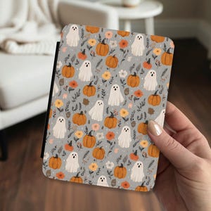May include: A rectangular e-reader case featuring a repeating pattern on a light gray background. The design includes white ghost illustrations, orange pumpkins, and small yellow and orange flowers with dark green leafy stems and thin black branches.