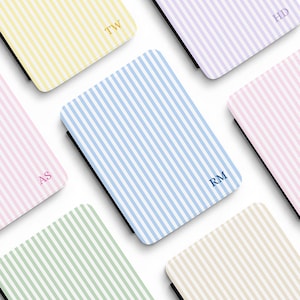 May include: Six rectangular cases featuring vertical stripes in yellow, lavender, blue, pink, green, and beige. Each case displays two-letter initials in a serif font, including TW, HD, AS, and RM, with a black edge visible on each item.