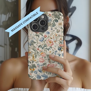 May include: A floral phone case with a cream background and a pattern of pink, blue, and yellow flowers and green leaves. The case is labeled "MAGSAFE COMPATIBLE" in a blue banner.