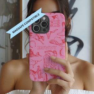 May include: Pink phone case with a red cowboy-themed design. The case features illustrations of cowboy boots, hats, horses, and the word "HOWDY". The case is labeled "MAGSAFE COMPATIBLE".