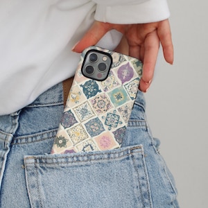 May include: A patterned phone case with a mosaic tile design in pastel colors of blue, purple, and yellow is partially visible in a denim pocket. The case has a black border and a camera cutout.