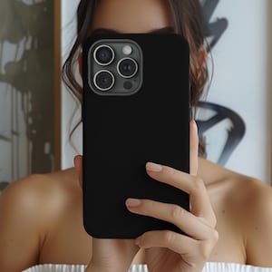 May include: A black phone case with a camera lens cutout. The case is being held by a person's hand.