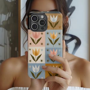 May include: A colorful phone case featuring a floral pattern with tulips in various colors, including pink, yellow, and white, set against a patchwork of pastel backgrounds. The case has a black border and a camera cutout.