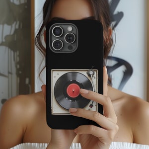 May include: Black phone case with a vintage record player design. The record player has a black turntable with a red label and a silver tone arm.