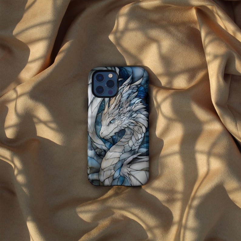 May include: A phone case featuring a white dragon with blue accents. The case has a stained glass design and depicts a dragon with its head turned to the side.