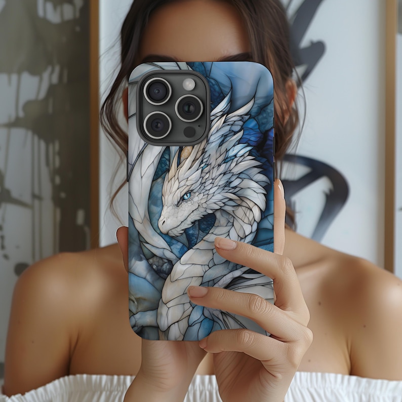 May include: A white and blue phone case featuring a dragon design. The dragon is white with blue accents and has a blue eye. The phone case is made from a hard plastic material.