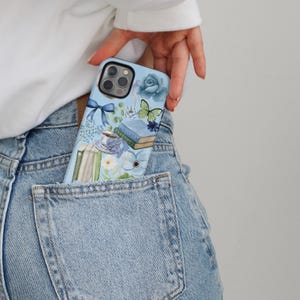 May include: A blue phone case with a floral and book design. The case features a butterfly, a rose, and a cup of tea.