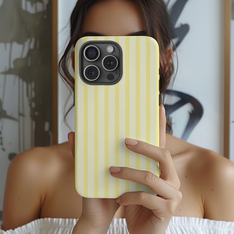 Pode incluir: Uma capa de telefone listrada amarela e branca para um iPhone.
