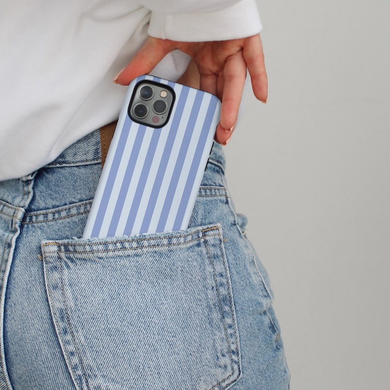 Peut inclure: Un &eacute;tui de t&eacute;l&eacute;phone &agrave; rayures bleues claires et blanches est partiellement visible dans une poche en jean. L'&eacute;tui de t&eacute;l&eacute;phone pr&eacute;sente un motif &agrave; rayures verticales. L'&eacute;tui de t&eacute;l&eacute;phone est de couleur unie avec une finition brillante.