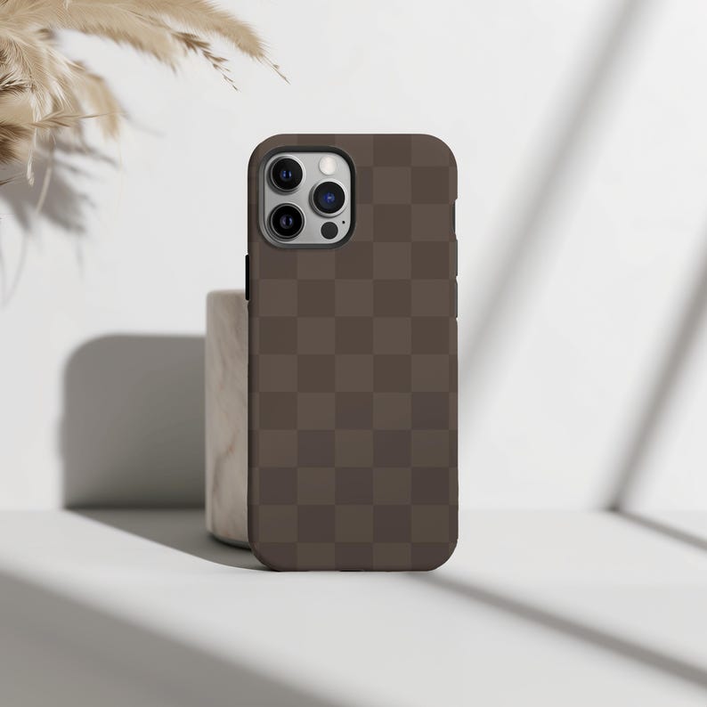 May include: A brown checkered phone case for an iPhone with a camera bump.