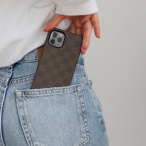 May include: A brown and black checkered phone case in a back pocket of blue jeans.